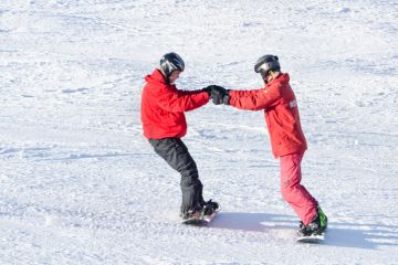 BUKOVEL, UKRAINE- 27 JANUARY 2018: Instructor teaches a guy to ride a snowboard