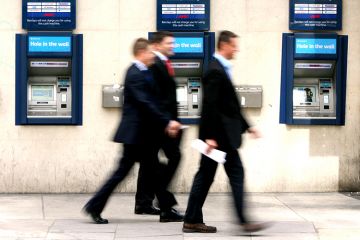 Businessmen walk past cash machines