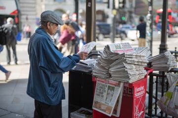 Elderly newspaper salesman in London street