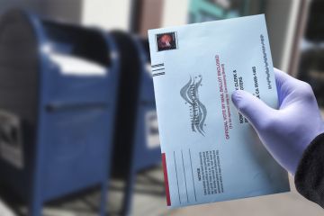 Person drops ballot into ballot box