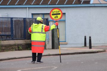 Lolly pop man holding "stop" sign 