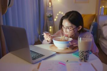 Asian woman eating ramen alone