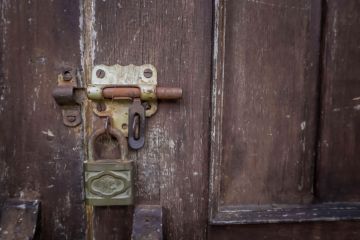 Unlocked padlock on wooden door