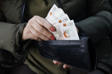 Hand of a woman holding sterling bills in her wallet