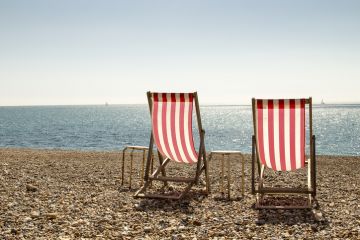 Two empty deckchairs on a stony beach to represent brain drain of graduates from English coastal towns 