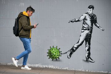 male student walking past wall mural
