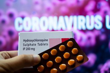 Photograph of hydroxychloroquine sulphate tables in a white coloured box in front of a red coloured board with coronavirus outbreak mentioned
