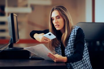 A woman photographs someone's essay, symbolising plagiarism