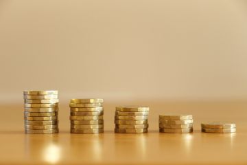 Shrinking piles of pound coins, symbolising financial stress