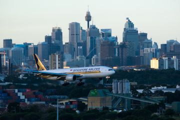Sydney Australia May 13, 2014 Boeing 777 wearing Singapore Airlines livery approaching for landing at Kingsford Smith airport at Dusk , with the city Skyline in the background