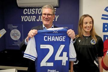 Photo of Sir Keir Starmer holding up a football shirt that says “Change” on it