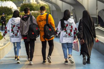 The youth in Tehran stroll through the city. A cheerful group of Iranian young people. Back view.
