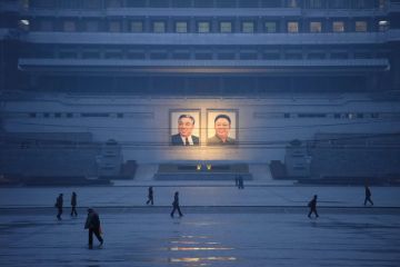  Pedestrians walking past the portraits of late North Korean leaders Kim Il Sung and Kim Jong Il across Kim Il Sung square as a metaphor for article offers rare look inside a North Korean university