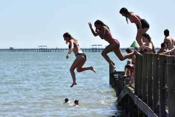 People jumping from a jetty into the sea in Southend-on-Sea, England illustrate Value of domestic students almost halves at some UK universities