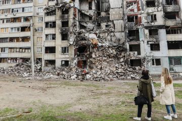People looking at damaged residential buildings in Ukraine to illustrate I’ve finally quit the UCU after its hard-left motion on Ukraine war