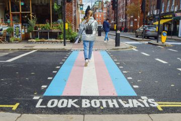 A woman walks along a pedestrian crossing with trans flag colours in Bloomsbury. to illustrate Trans rights debate ‘is distracting union’