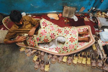 A Pakistani shoe maker, Hameed, sits inside a giant shoe at his shop in Lahore.