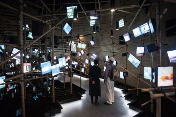 Exhibition hall with irregular arrangement of multimedia screens in Milan to illustrate Major universities play catch-up as Italian students move online