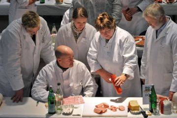 Food testers evaluate products during a quality check for ham and sausage as a metaphor for quality and control