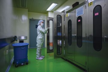 A lady putting on protective clothing required to enter a testing lab