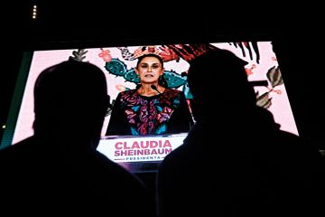 Supporters of Mexico's presidential candidate for Morena party Claudia Sheinbaum look at her on a screen to illustrate Mexican scholars hope for change as scientist takes presidency