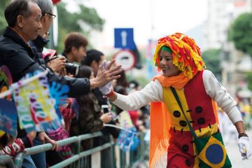 An actor gives a 'hi five' to a spectator in Macao, south China to illustrate ‘We see Macao as a bridge between West and China’