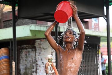A child is taking a bath from a roadside water pipeline during a heatwave in Dhaka, Bangladesh