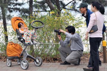 A South Korean man takes a photo of his baby sitting on a pushchair during their family picnic to illustrate Korean excellence plan shortlist drafted
