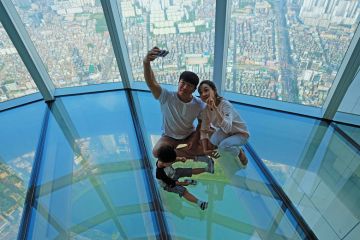 A Korean family taking selfie photo at the glass floor observatory of Lotte World Tower  for Top Korean universities more ‘glass floor’ than ‘social ladder’