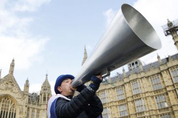 A demonstrator holds up a megaphone  near the Houses of Parliament to illustrate the Free speech bill fans urge ministers to force home right to sue