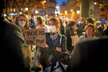  A member of the crowd watching the National Tribute to the murdered school teacher Samuel Paty holds a placard reading 'Do not touch my Professor' at Place de la Sorbonne on October 21, 2020 in Paris, France.