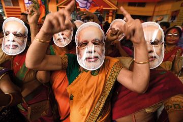 Supporters wearing masks of Indian Prime Minister Narendra Modi dance as they celebrate on the vote results day for India's general election to illustrate Academic walkout raises questions about university thinktanks