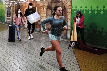 Student running by others wearing face masks to illustrate Splash overseas fee cash back on students, Australia urged