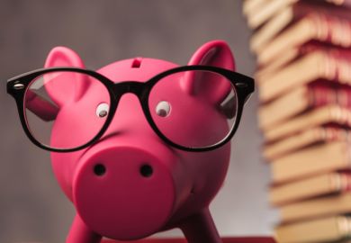 A piggy bank beneath a pile of books, symbolising open access costs