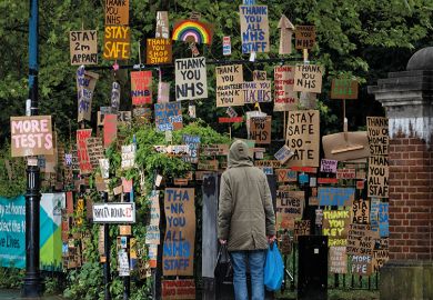 A member of the public walks past a display of signs relating to Covid
