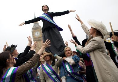 Feminists dressed as The Suffragettes at a protest for women's rights in London. One is standing on the others. To illustrate how a boycott of a feminist title failed to consider its likely impact on early career researchers