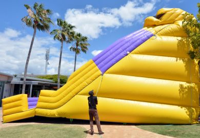 Gold Coast, Australia - October 19, 2014: Worker inflates a slide bouncy castle.