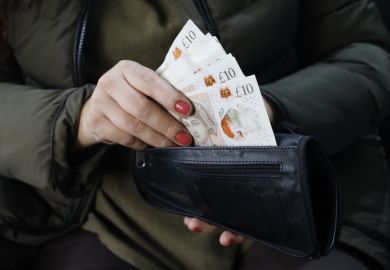 Hand of a woman holding sterling bills in her wallet