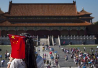 Young Chinese girl with a Chinese Flag in her head at the Forbidden City in the city of Beijing.