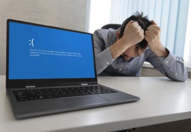 showing error blue screen on the Laptop against the background of an angry upset man clutching his head