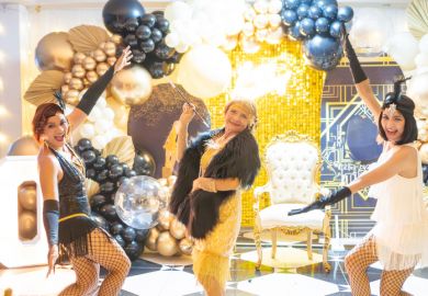 Three women in vintage 1920s attire dancing at a Gatsby-themed celebration.