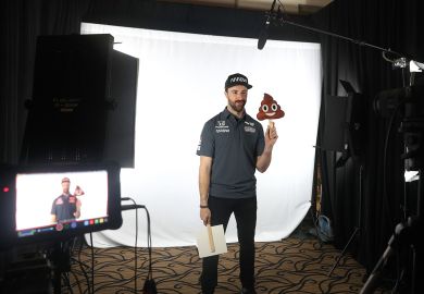 James Hinchcliffe holds a poop emoji while filming on a screen to illustrate Academics despair as ChatGPT-written essays swamp marking season