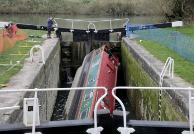 People look at a narrowboat that has capsized in a lock on the Kennet and Avon Canal 