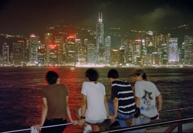 Four people enjoying a night view of the famous Victoria Harbour to illustrate Chinese school-leavers look closer to home for international study