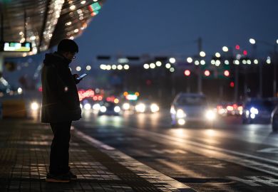 A man uses a smartphone as he waits for a bus at a bus station in Seoul, South Korea to illustrate Korean universities rocked by deepfake pornography scandal