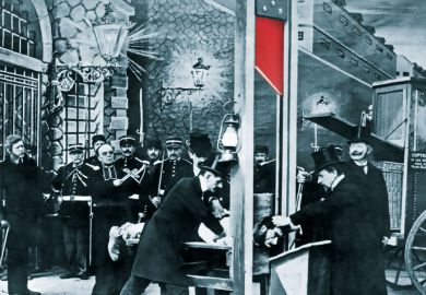 French postcard about 1900 showing a mock-up execution in a photographer's studio to illustrate Why should academics risk their livelihoods in contributing to books?