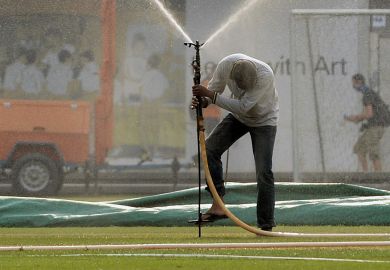 A man tries to place a water sprinkler on a field in Singapore