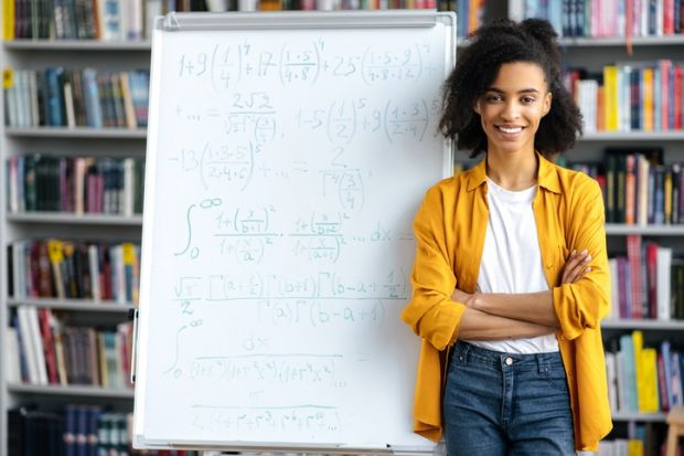 A black academic in front of a white board