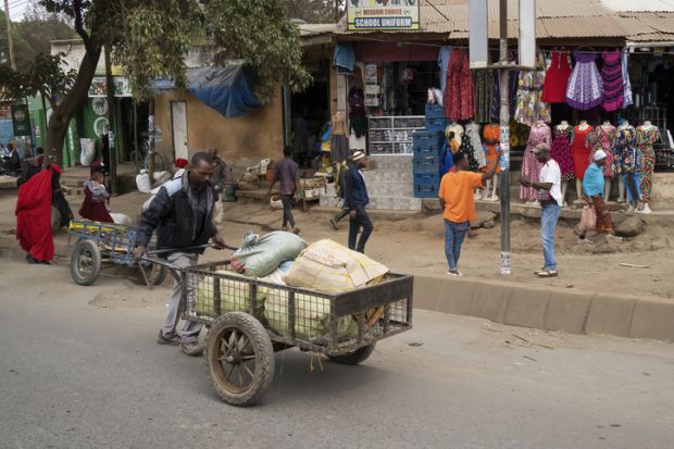 A porter pushing a cart full of parcels in the main street of Arusha, Tanzania