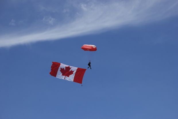 A Skyhawk team member is seen in the image with the flag of Canada, “The Maple Leaf” in tow at the beginning of the performance at the 2016 Duluth Air Show